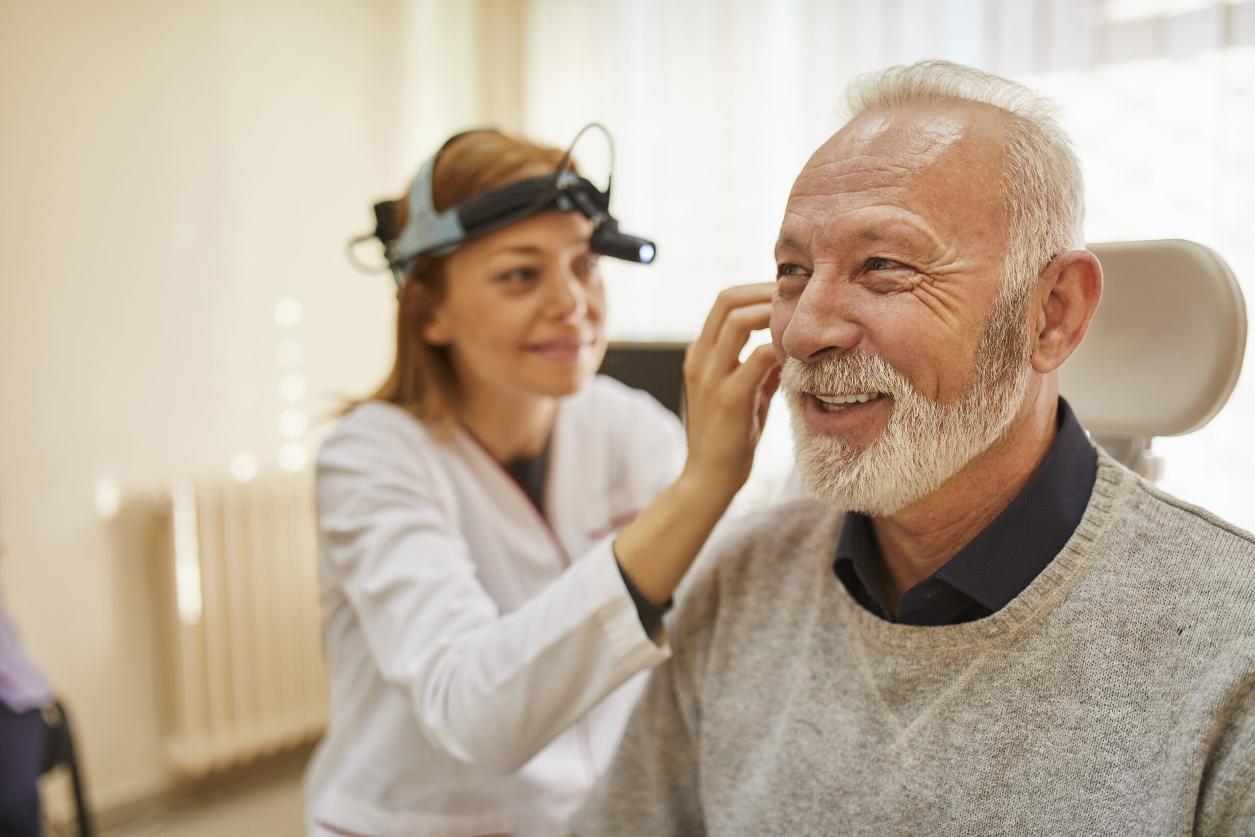 ENT physician examining ear of a senior man